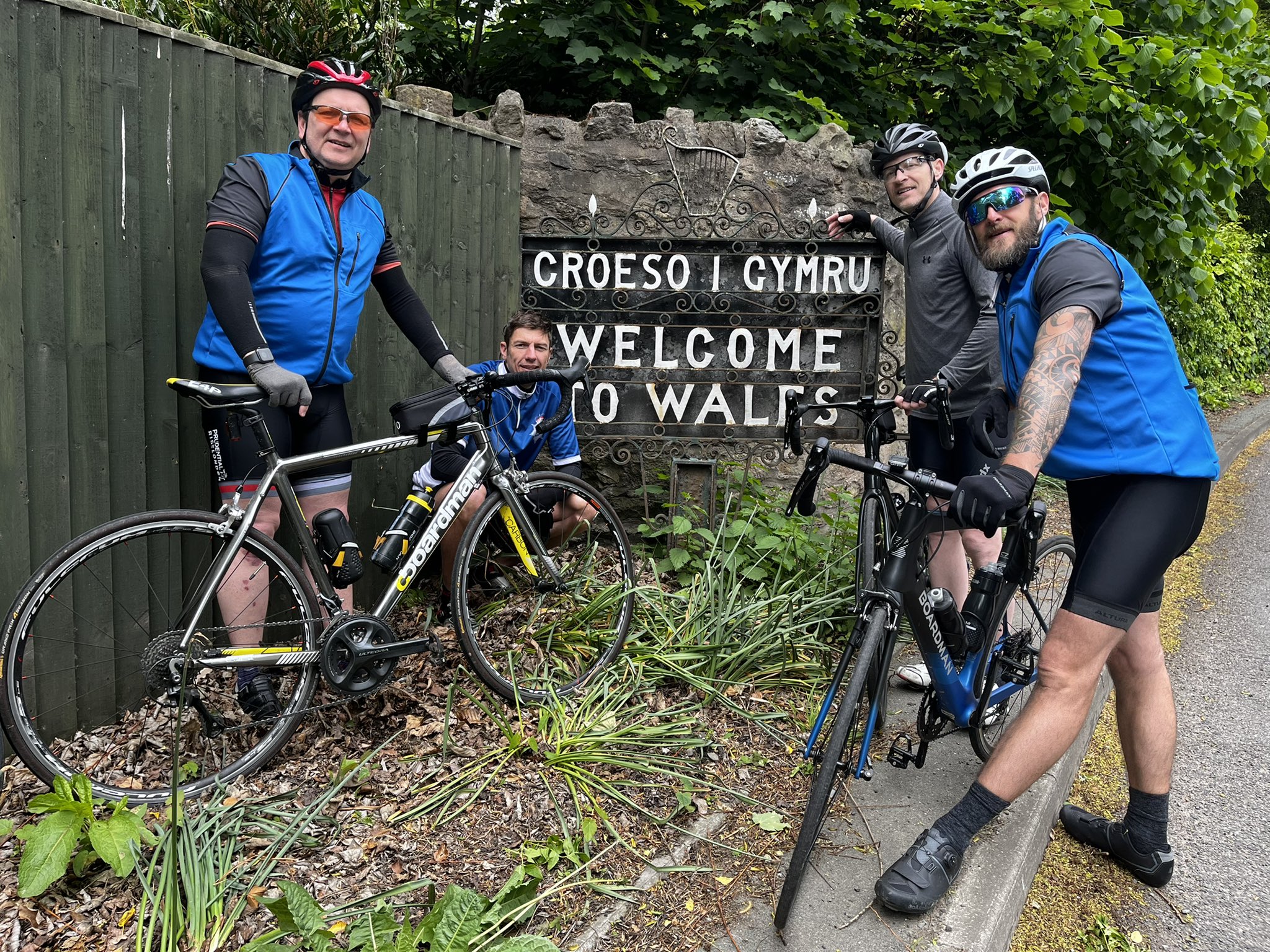Image: the men next to 'Welcome to Wales' sign