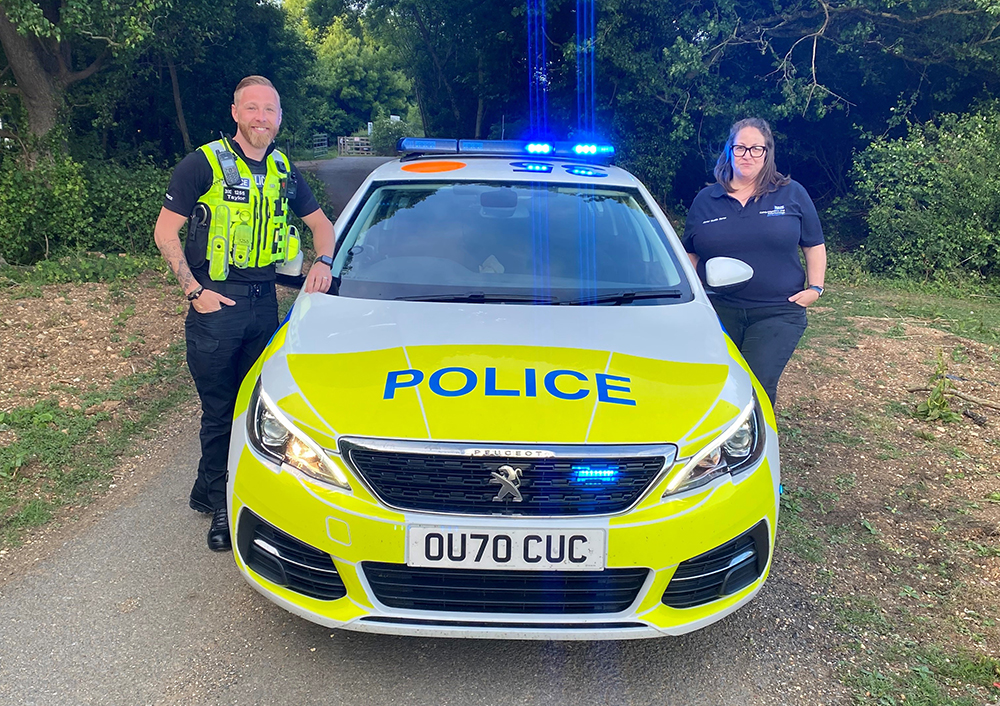 An officer and a mental health practitioner standing next to a police car