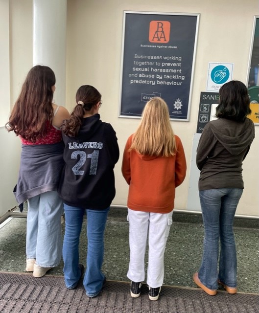 Four girls looking away at Business Against Abuse poster