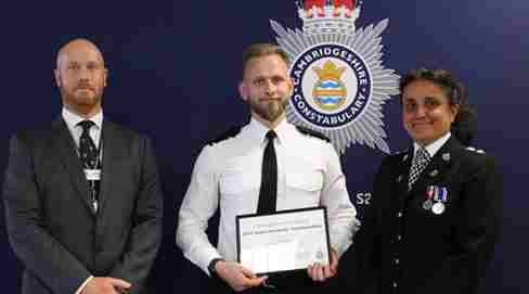 Sam holding a framed certificate with 2 senior officers