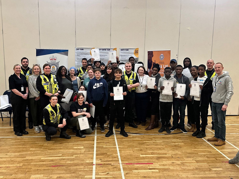 A group of young people with police officers and volunteers