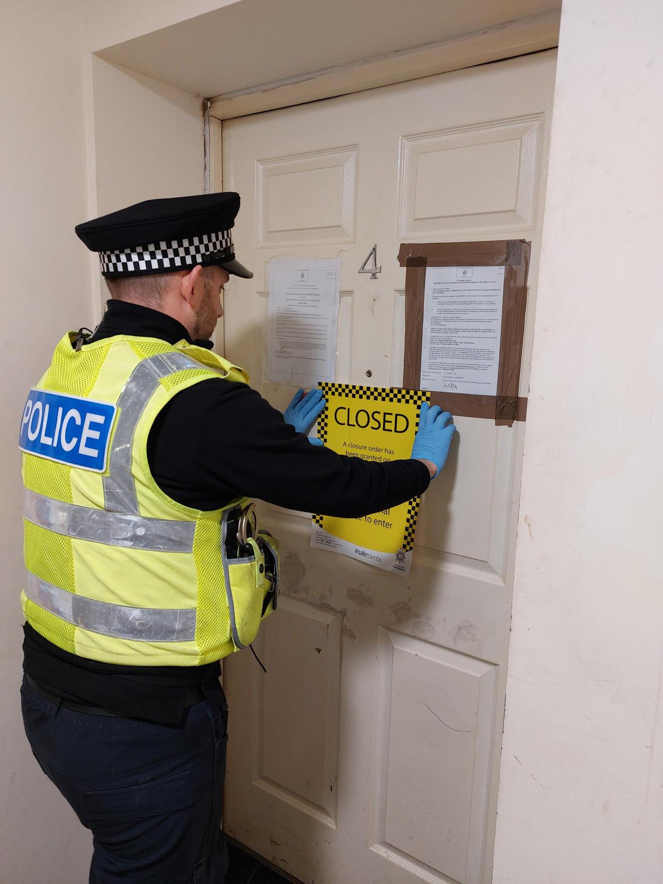 Police officer taping up closure order signs