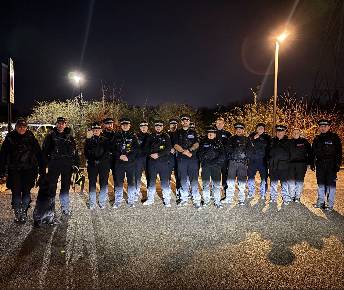 Uniformed police officers stood in a line outside at night