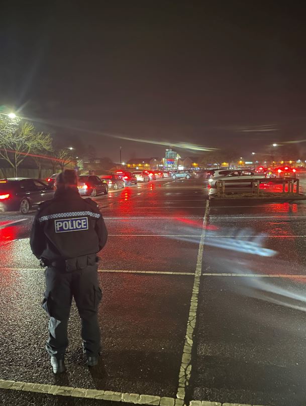 Cars leaving a carpark and watched by police officer