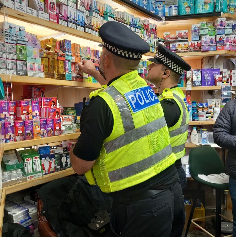 Two police officers looking at vapes in a shop