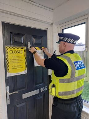 Police officer putting up closure order signs