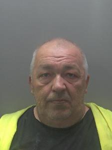 A custody photo of a middle-aged man wearing a high-vis jacket. 
