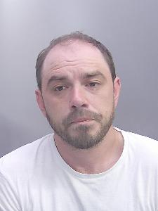 A custody photo of a man looking glum. 