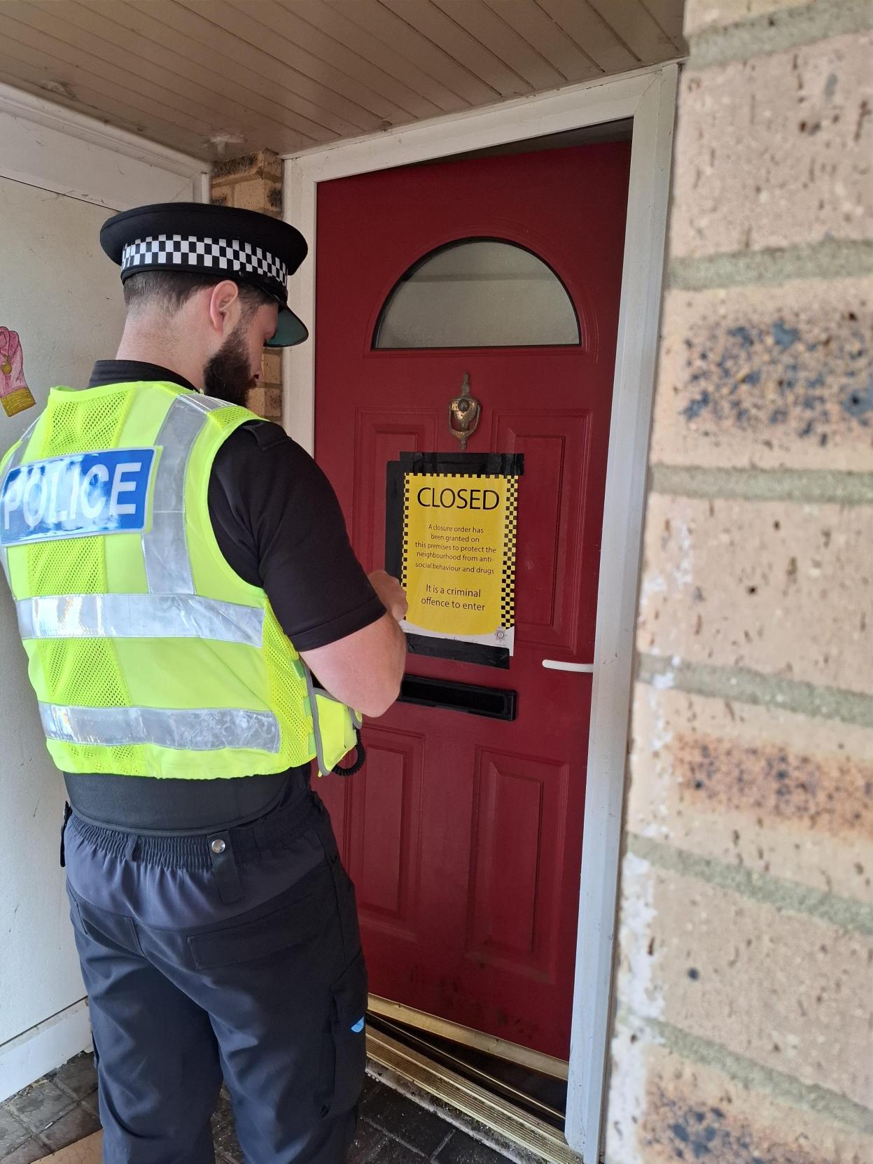 Police officer putting up closure order signs