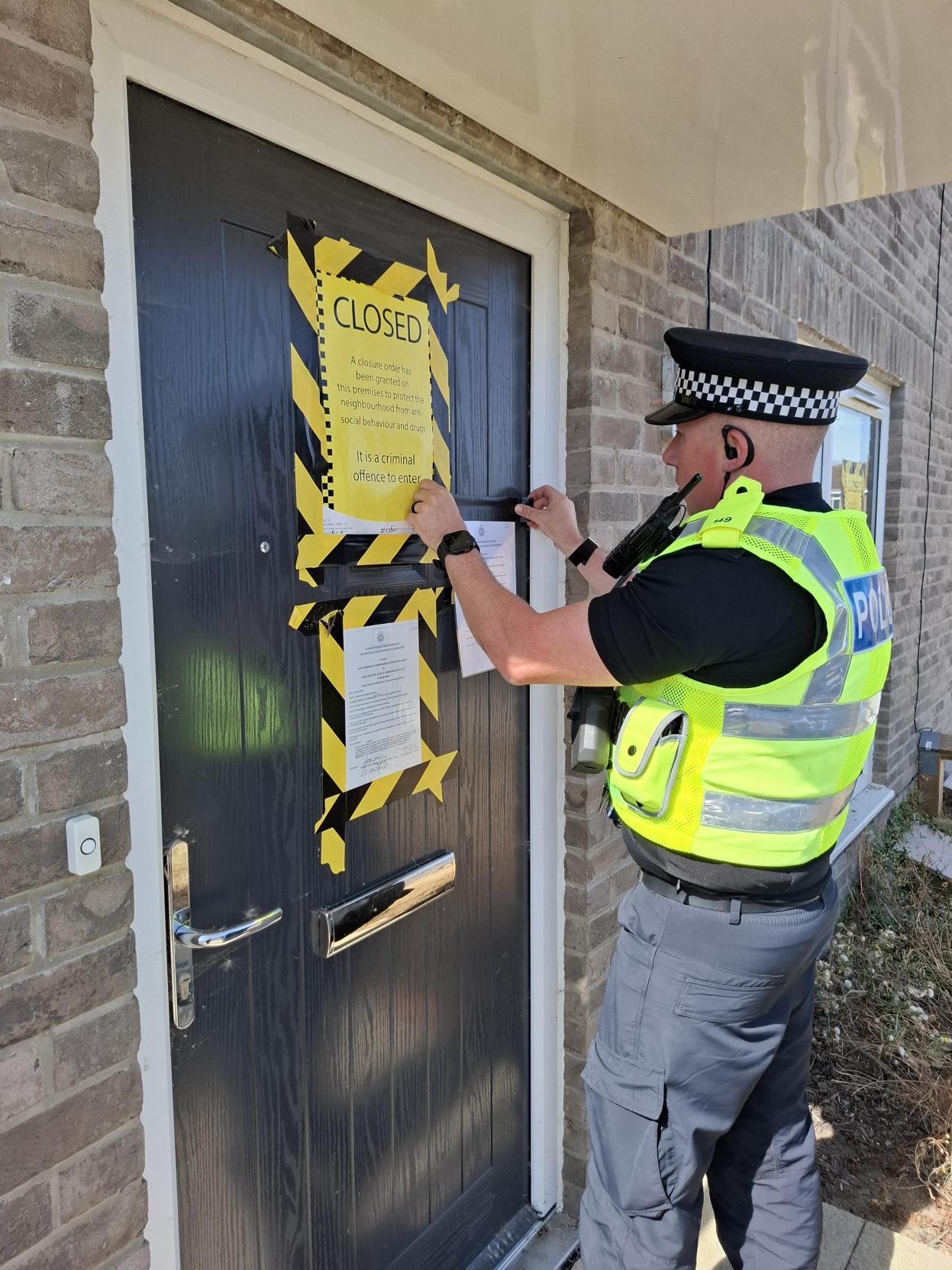 Police officer putting closure order signs up
