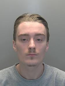 A custody photo of a young man looking glum. 