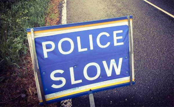Blue roadside sign with the words 'police slow' in white