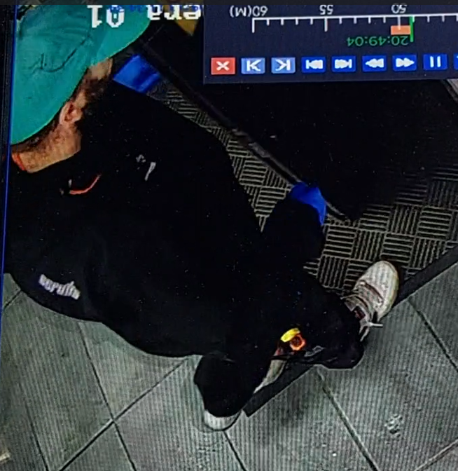 CCTV image of a man in dark clothing with a green cap
